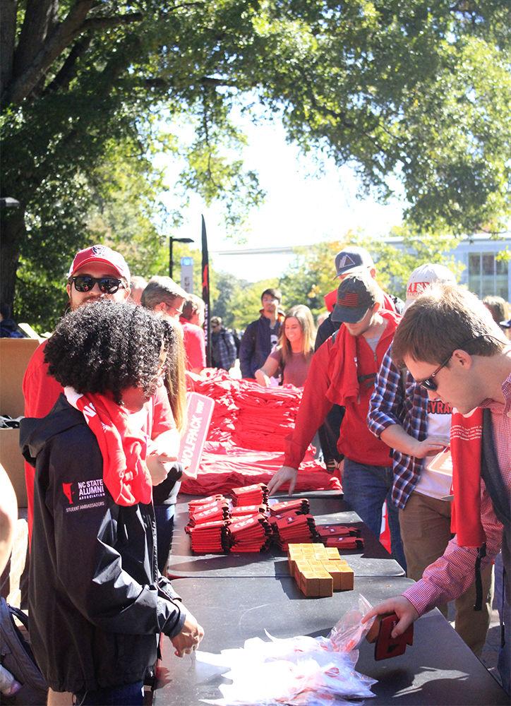 Free shirts, signs, mugs, and brick-shaped stress balls are passed out during the Red and White Week Kickoff in Wolf Plaza on Monday, Oct 29.&#160;