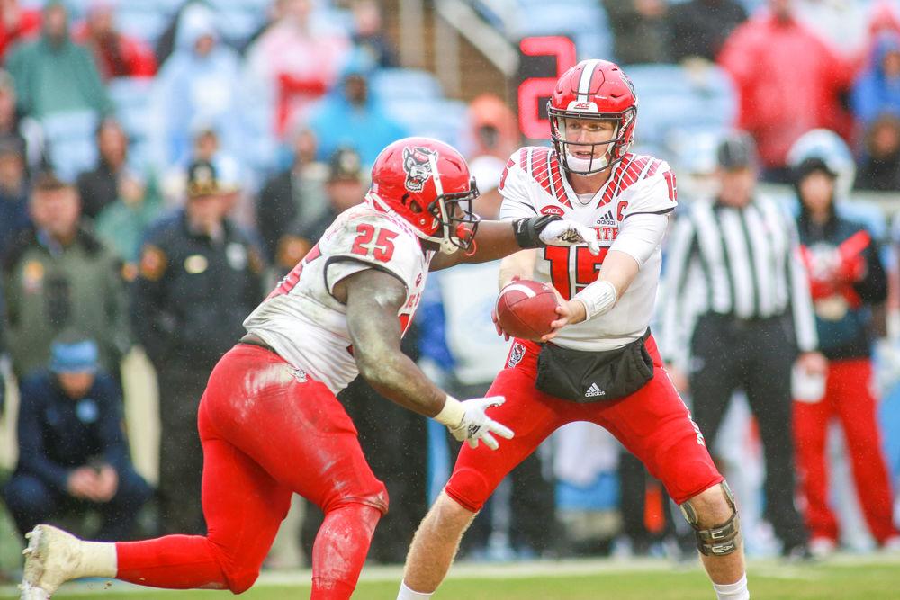Graduate quarterback Ryan Finley hands the ball off to senior running back Reggie Gallaspy Jr. Gallaspy had a career day with 129 yards on 27 carries. The Wolfpack were tested by the Tar Heels, but came away with a 34-28 overtime win on Saturday, Nov. 24 in Kenan Memorial Stadium.