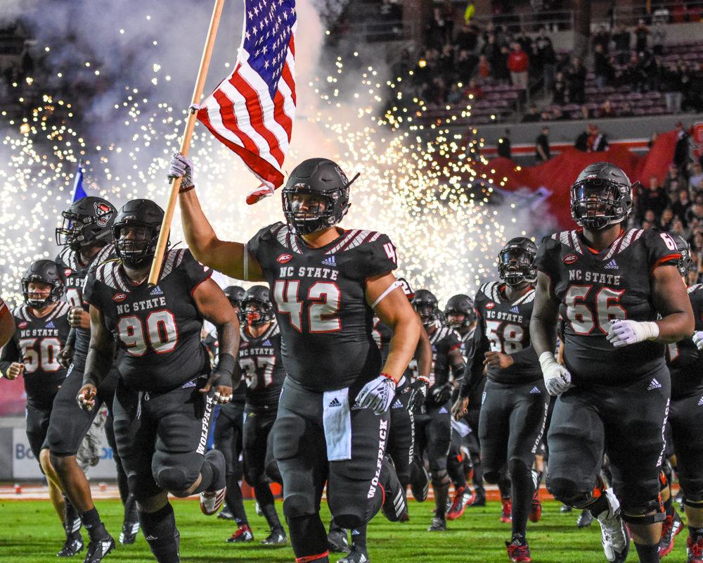 Redshirt freshman defensive tackle Danny Blakeman holds up the American flag as NC State takes the field on senior night on Thursday, Nov. 8, in Carter-Finley Stadium. The Wolfpack lost to Wake Forest 27-23.