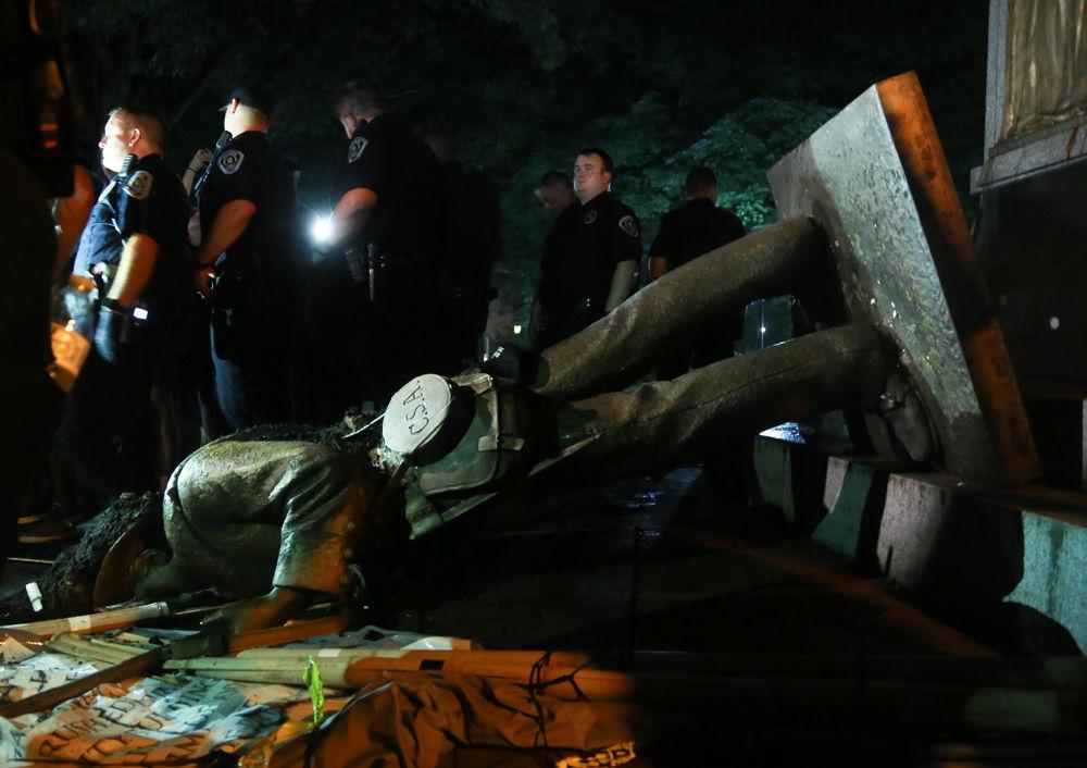 UNC Department of Public Safety officers stand guard around the fallen statue on McCorkle Place. Silent Sam was pulled down by protestors during a rally Monday, Aug. 21.