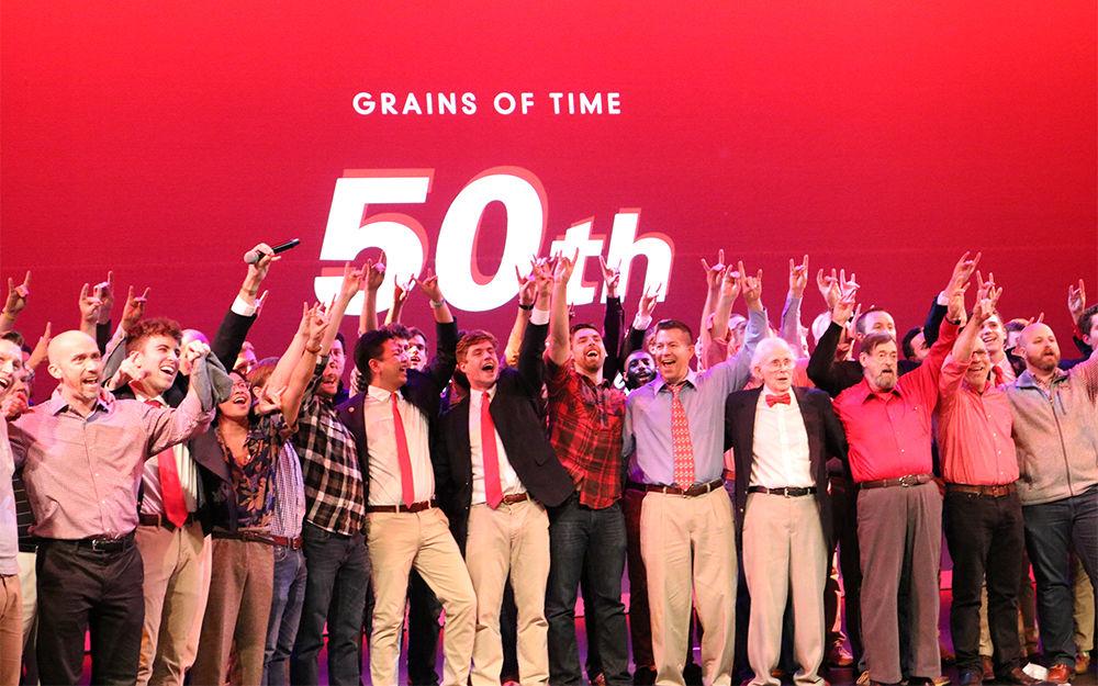 Different generations of Grains of Time hold up their wolfies at their 50th anniversary concert on Saturday, Dec. 1, 2018 at Talley Student Union.