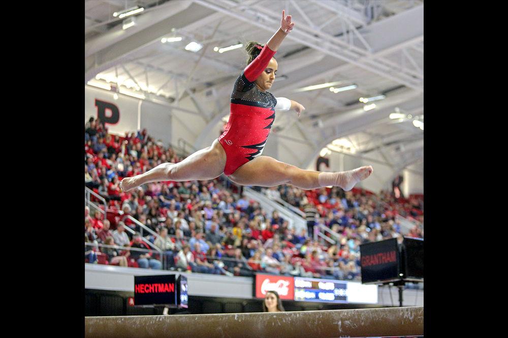 Sophomore Drew Grantham performs a leaping split on the beam on Saturday, Feb. 17, 2018 in Reynolds Coliseum. Grantham scored a 9.875 at the meet against UNC-Chapel Hill.