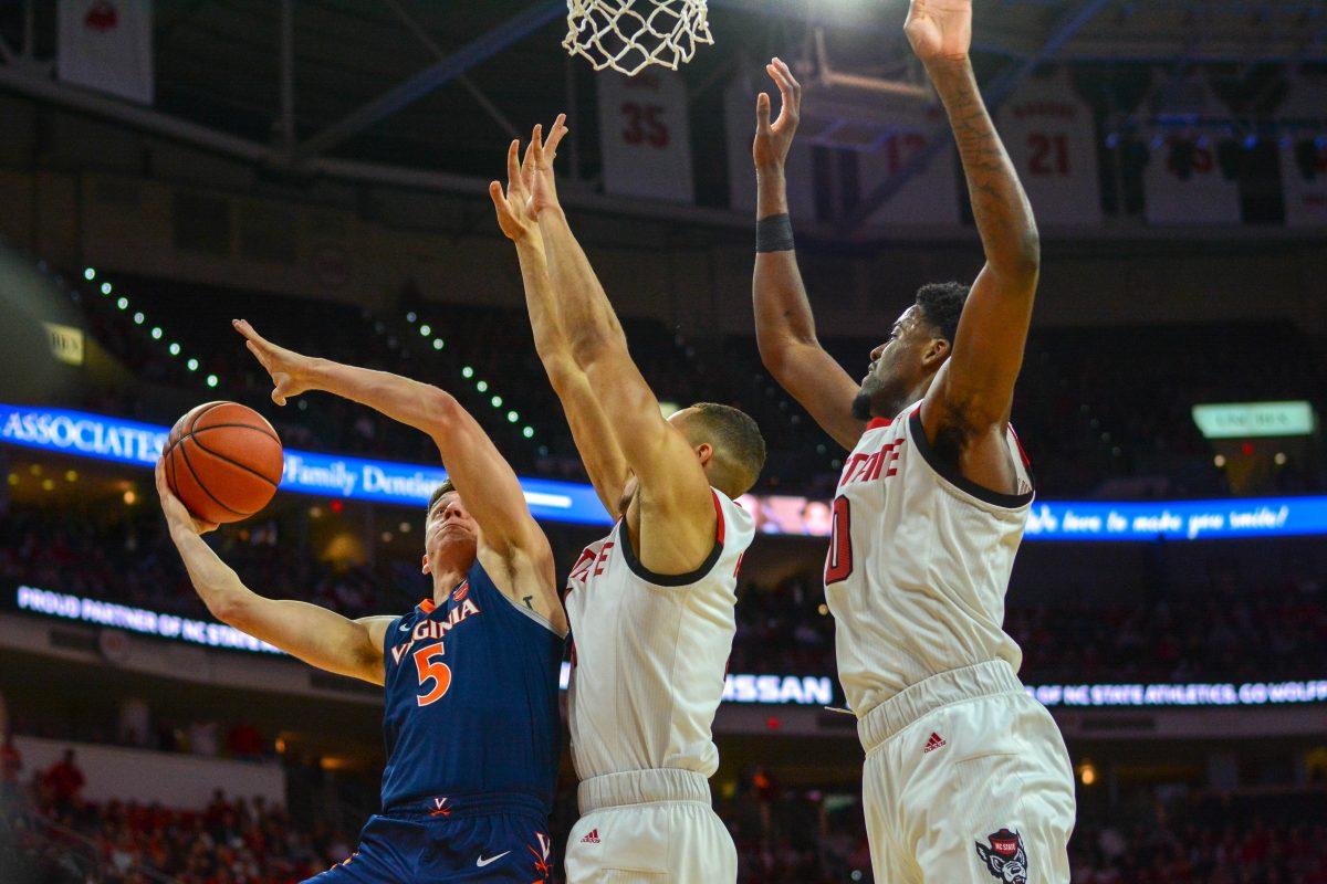 Redshirt sophomore forward DJ Funderburk and freshman forward Jericole Hellems attempt to block Virginia guard Kyle Guy in the Wolfpack's 66-65 overtime loss against Virginia at PNC Arena on January 29.