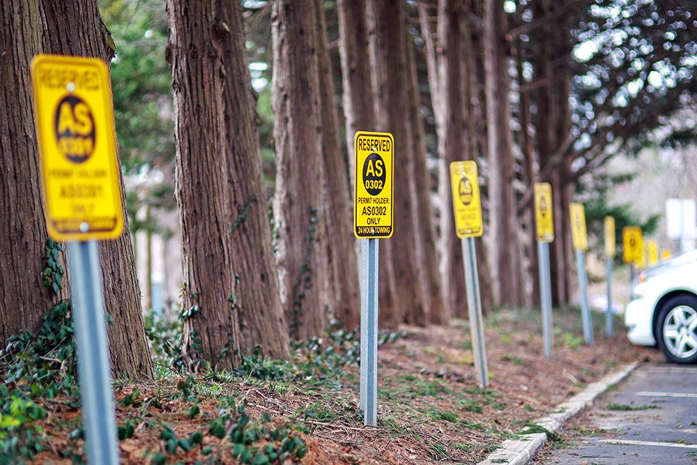 Assigned space parking signs stand along the road bordering the Strolling Professor statue on Jan. 27, 2019. Student workers&#8217; need for parking at workplaces that do not offer student parking may cause redundancies in the parking passes being provided.