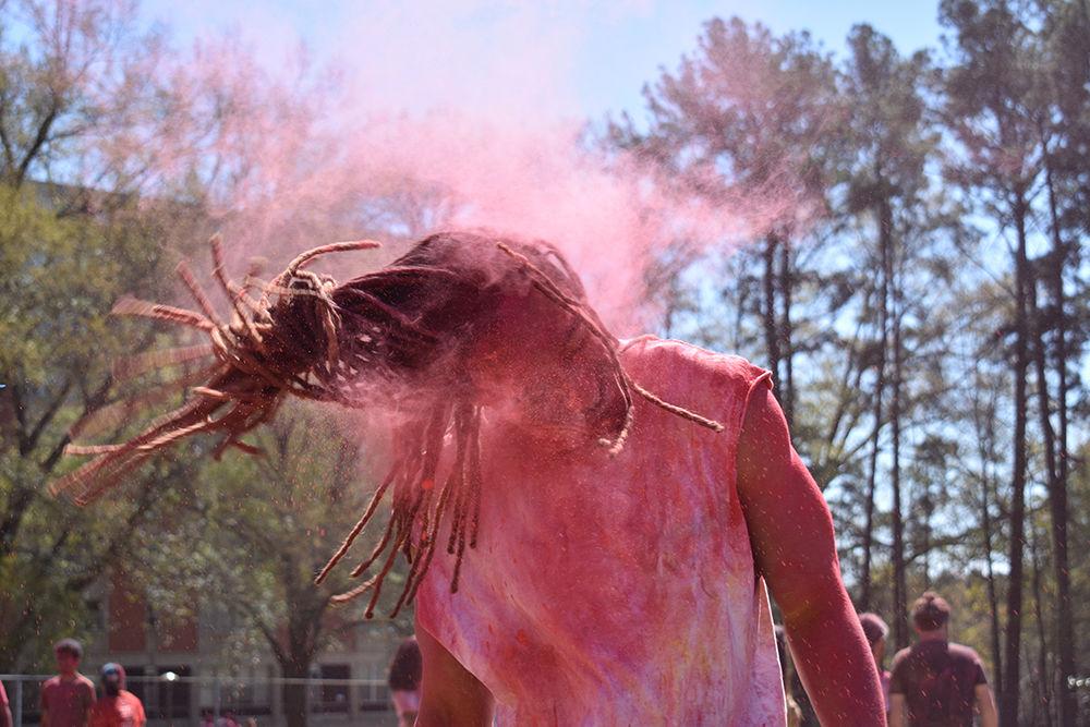 Local Derrick Rudolph shakes clouds of pink colored powder out of his hair at the Holi Festival celebration on Lee Field on Sunday, March 24.