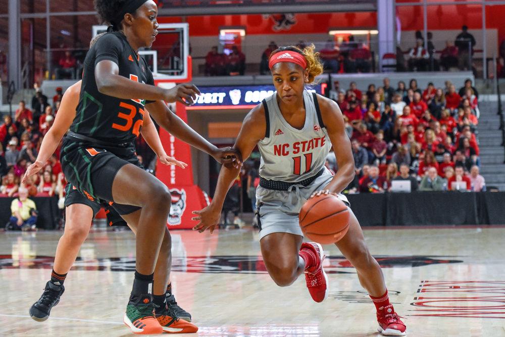 Graduate guard Kiara Leslie drive the ball past Miami forward Beatirice Mompremier. The Wolfpack won 70-68 with Leslie scoring 12 points on Sunday, March 3 in Reynolds Coliseum.