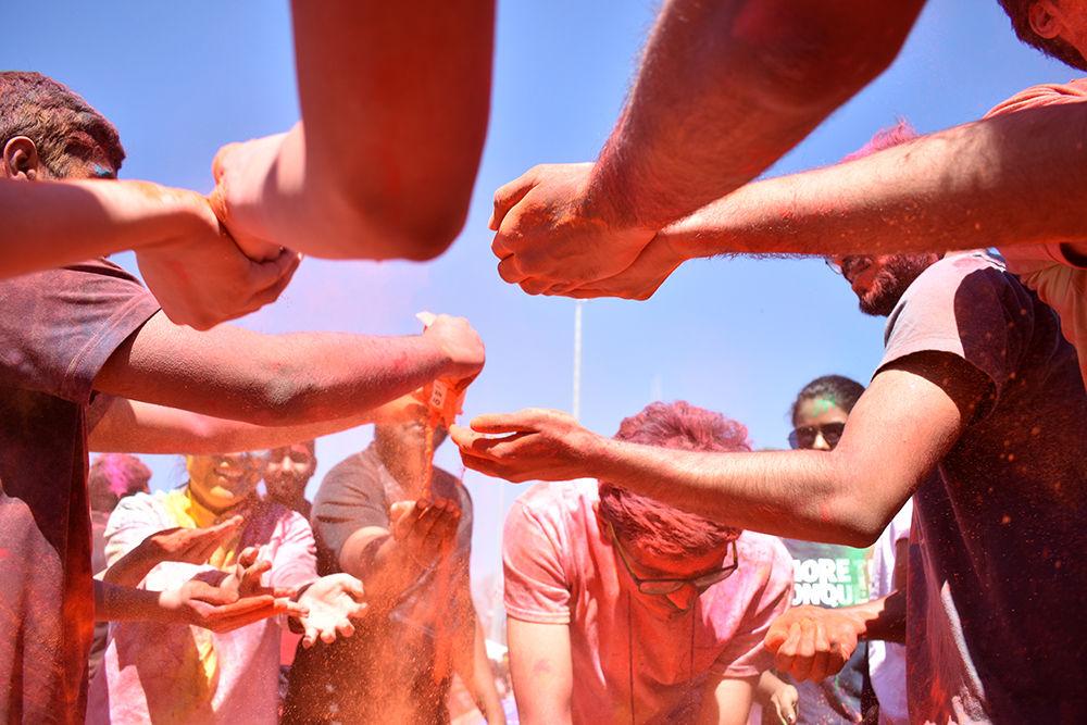 Reaching hands are filled with orange powder used for celebrating the Indian holiday of Holi on Sunday, March 24 on Lee Field.