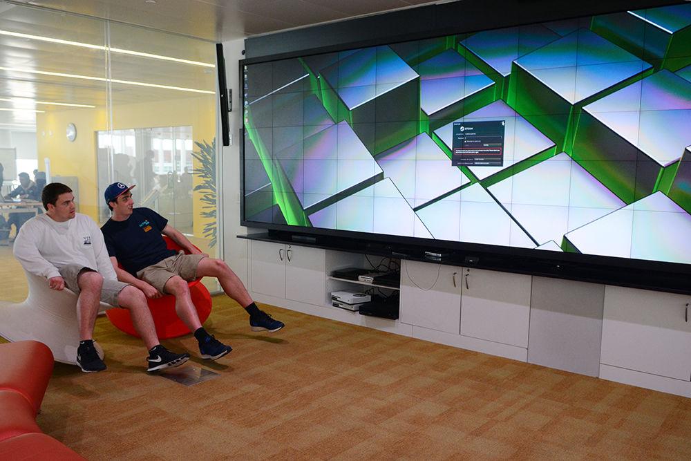 Prior to renovation, Luke Watson, a freshman in exploratory studies, and Eric Scollard, a freshman studying finance, view a large micro-tiles screen while sitting on video game roller chairs in the Game Lab during a tour of Hunt Library March 17, 2017.