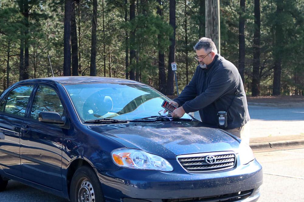 Property security officer Matthew Heater&#160;writes a citation for a car on Central Campus on Friday, March 22.