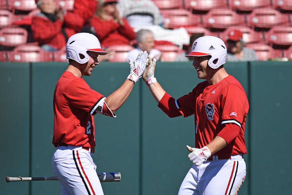 Sophomore outfielder Jonny Butler and junior pitcher Jason Parker high-five each other during the game against Minnesota on Saturday, March 2, at Doak Field. The Wolfpack won 3-2.