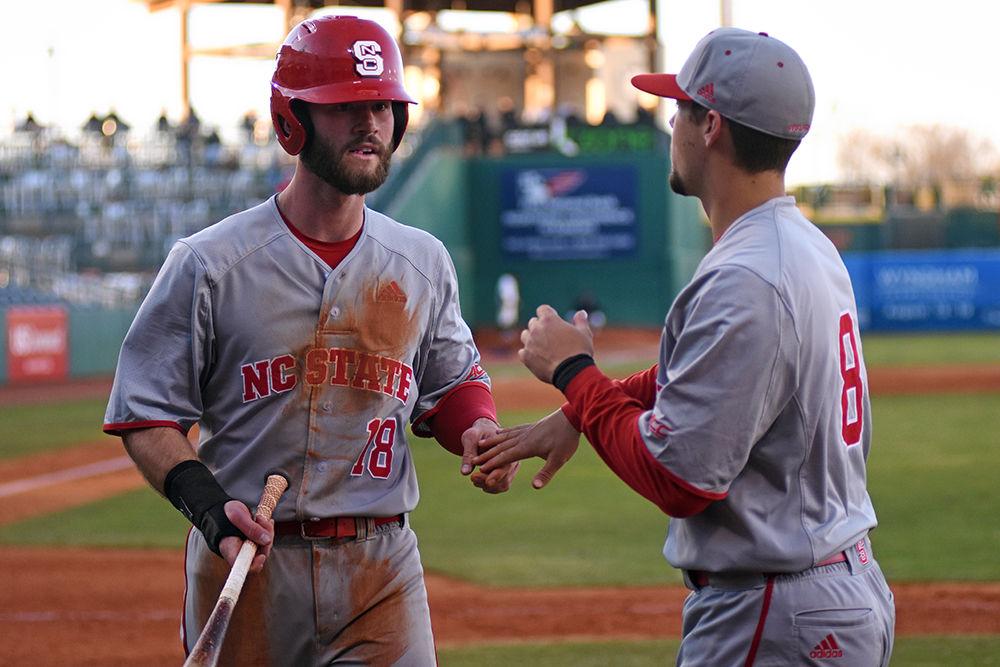 Senior infielder Evan Edwards is congratulated by teammate junior infielder Will Wilson after the former earned a run during the game against NC A&amp;T on March 27, at First National Bank Field at Greensboro. The Wolfpack beat the Aggies 12-3.