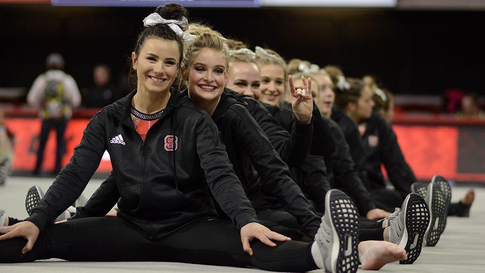 The NC State gymnastics team smiles while waiting for final scores at the meet against Western Michigan and William and Mary on Friday, Feb. 22 at Reynolds Coliseum. The Wolfpack won with a score of 195.350, and senior Caitlyn Fillard placed first all around.