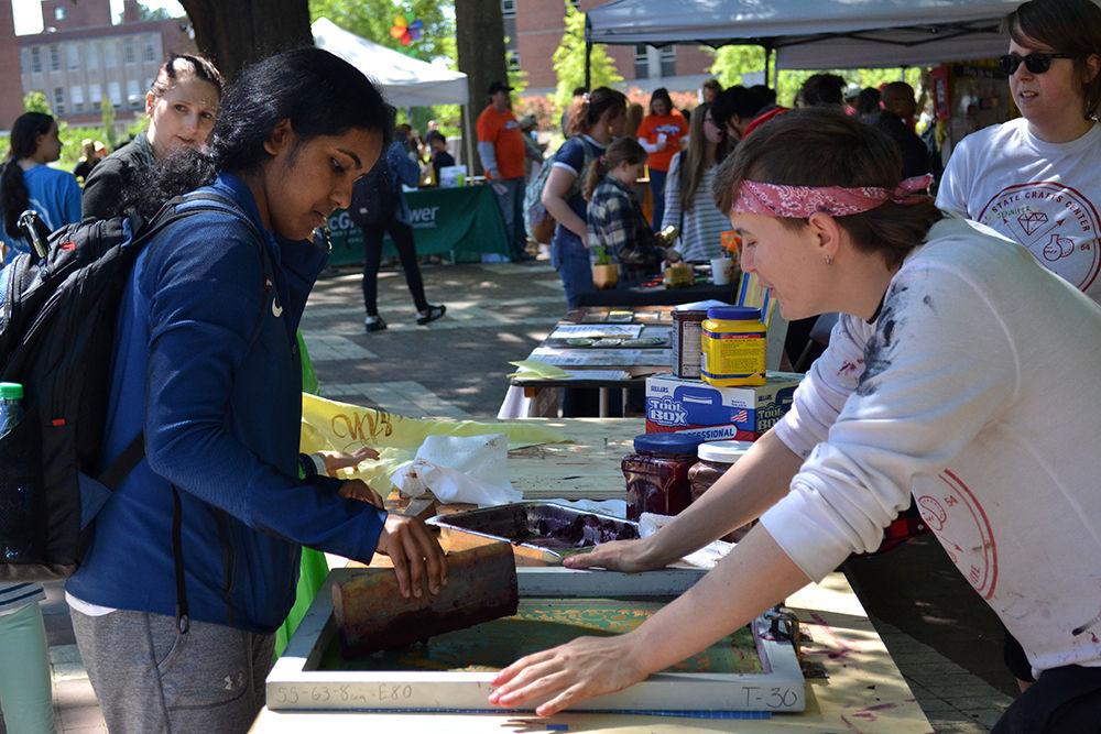 Ashley Mathew, a second-year studying biological science, screen prints with a beet based dye under the direction of Katy Walls, an employee of the NC State Craft Center, at the Earth Day Fair on Monday, April 22, at the Brickyard.