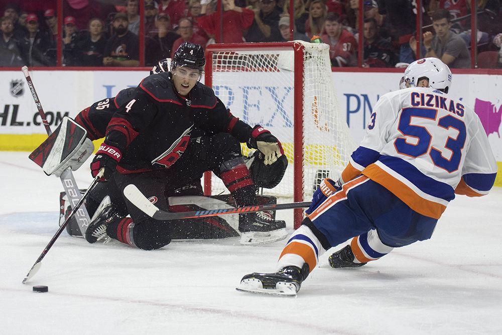 Defenseman Haydn Fleury pushes the puck away from goaltender Curtis McElhinney and Islanders forward Casey Cizikas, Friday, May 3 in PNC Arena. The Canes took down the New York Islanders, 5-2, in the second round.