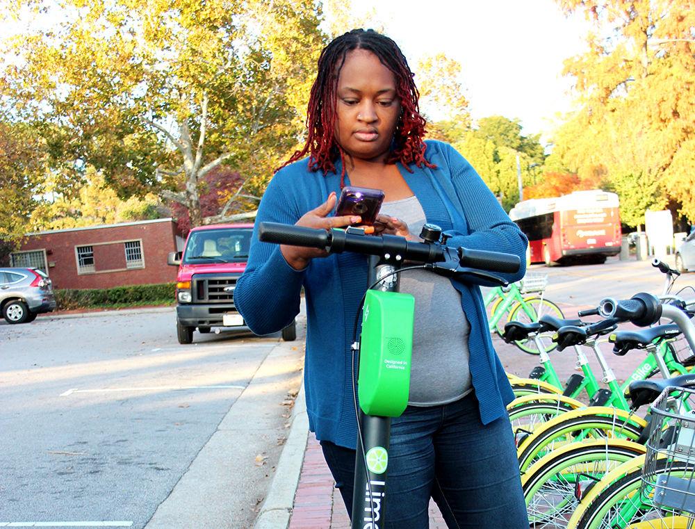 Shenita Covington charges a Lime-S scooter outside of Witherspoon Student Center on Tuesday, November 20, 2018. Lime-S allows users to rent the electric scooters and leave them anywhere once they are done using them.