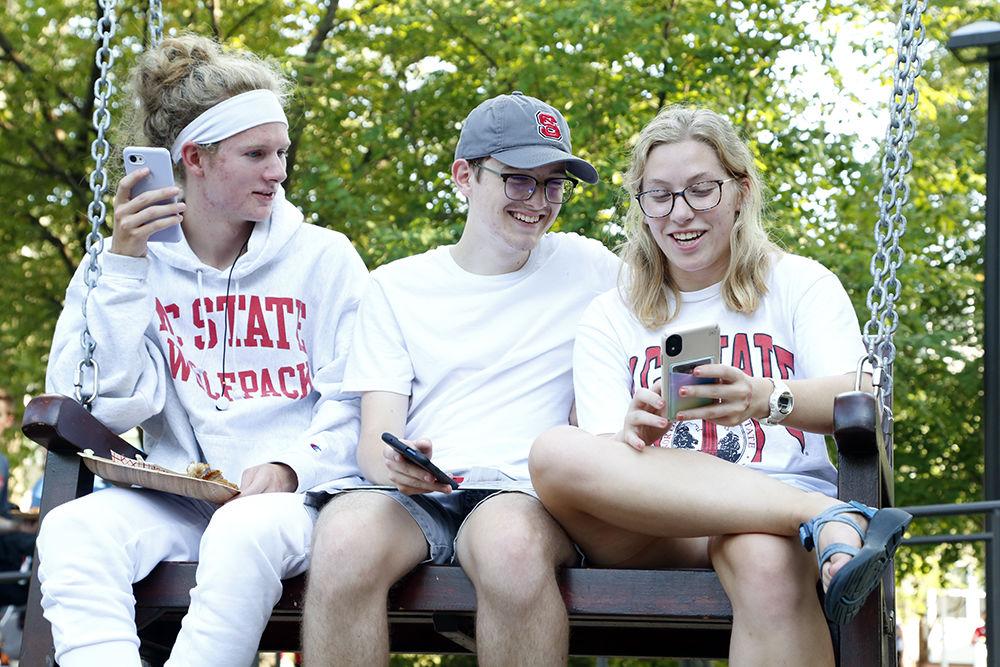 Shay, Eligh, and Eric share an instagram post on a swing bench at the All Amercan Meal on Tuesday, Sep. 10, 2019. Students were able to interact with the food vendors for various prizes.