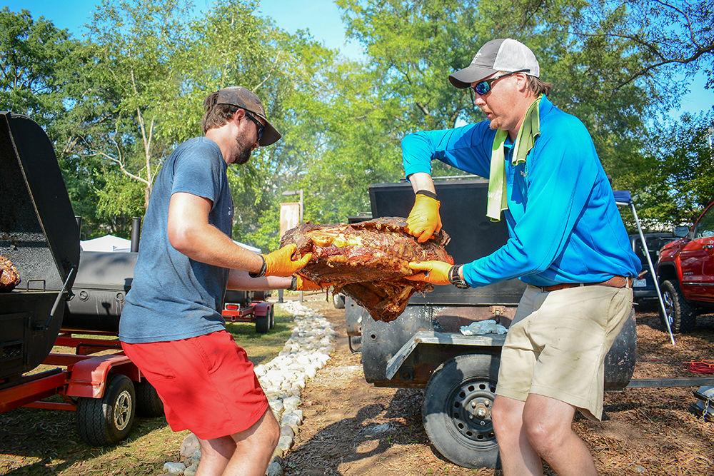 Glenn Issette and Matt Williamson, two members of the Q Masters, carry BBQ meat from the pit to the carving board during the All Carolinas Meal at Fountain Dining Hall on Tuesday, Sept. 10, 2019. The All Carolinas Meal is an annual event hosted by NC State Dining that highlights Carolina themed food, music, and farming.