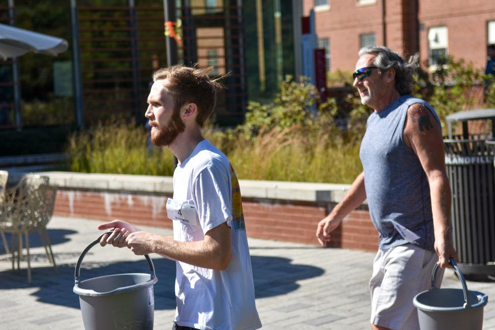 Alex Stotka passes Mark Vaughn in the Water Walk at Stafford Commons on Oct. 26, 2019. The Water Walk is an event where racers experience what it is like from a global perspective for the average women to transport clean water by walking two laps around the commons with a full bucket of water. Proceeds for this event go to support Wine to Water, an organization whose efforts go to bringing clean water to those in need.