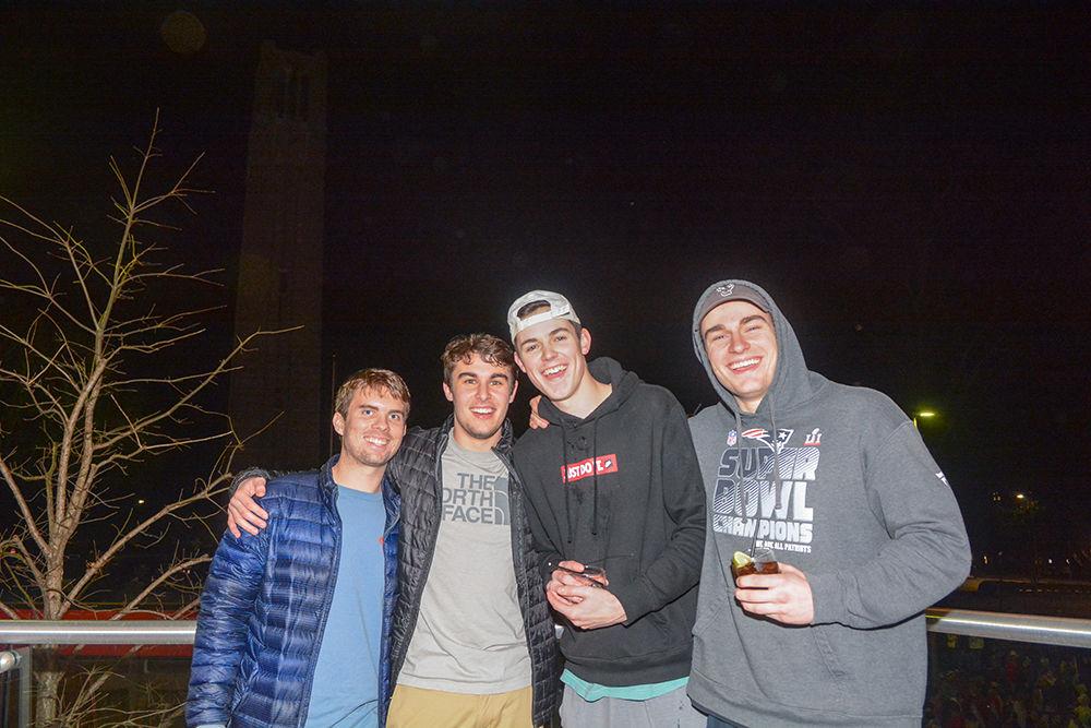 NC State students stand on the balcony of the XYZ Lounge to catch a glimpse of the Bell Tower rush after the 88-66 win over Duke on Wednesday, Feb. 19, 2020. Hillsborough Street flooded with Wolfpack fans in support of the men&#8217;s basketball team win.