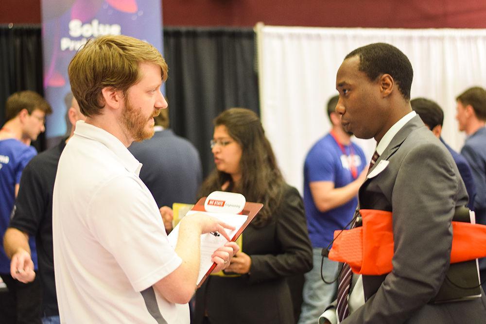 Andy Whitehorne, the head of system architecture at Werum speaks with Moses Gicheru, an applicant during the Engineering Career Fair on Wednesday, Feb. 5, 2020 at the McKimmon Center. The Career Fair helps students and attendees network with companies looking for employees and interns.