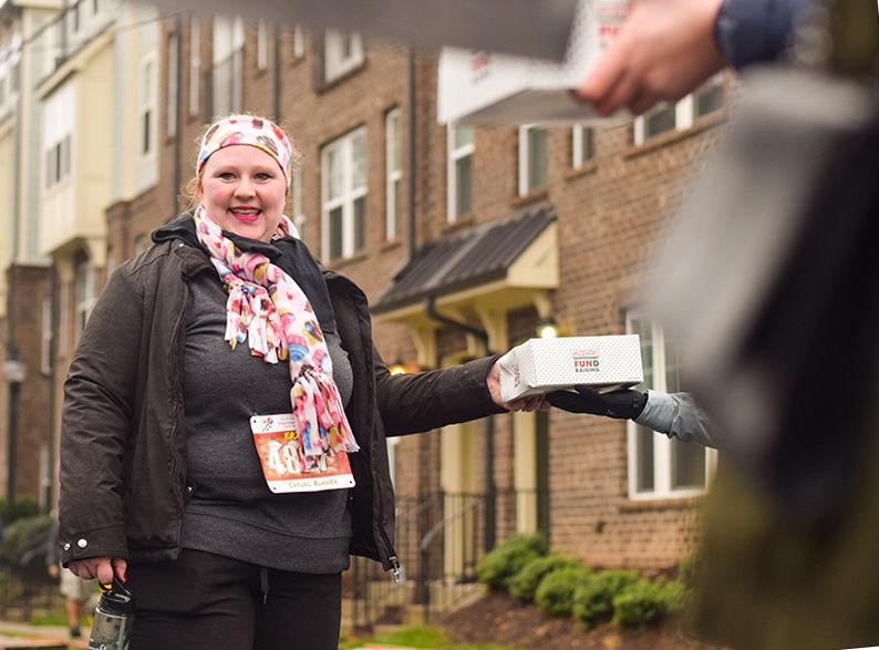 Casual runner Erin Snider picks up her doughnuts along the Krispy Kreme Challenge route on Saturday, Feb. 1, 2020. The Krispy Kreme Challenge benefits the UNC Children's Hospital.