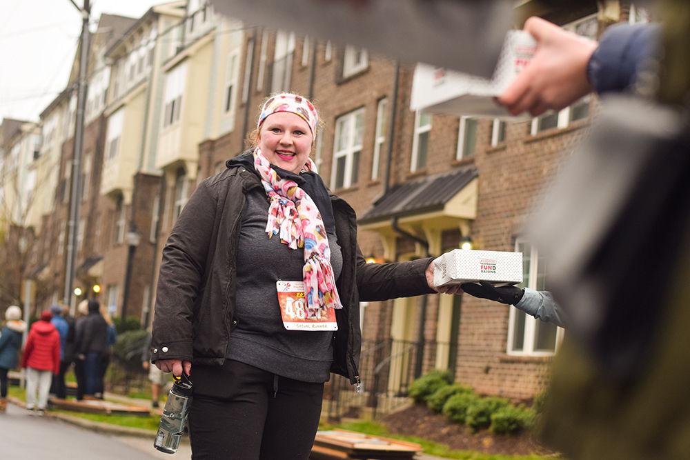Casual runner Erin Snider picks up her doughnuts along the Krispy Kreme Challenge route on Saturday, Feb. 1, 2020. The Krispy Kreme Challenge benefits the UNC Children's Hospital.