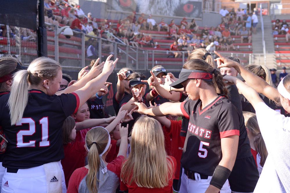 The NC State softball team includes young softball players in their pregame huddle at the game against Campbell on Wednesday, April 24. The Wolfpack lost to Campbell 6-4 at Dail Softball Stadium.