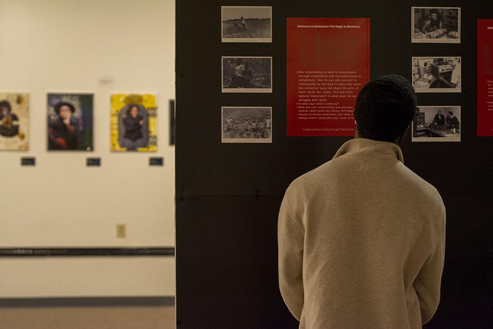 Ty Harris, a third year in zoology, looks at art on display at the Existence as Resistance: The Magic in Blackness exhibit. The exhibit opened on Tuesday, Feb. 18, 2020 in the African American Cultural Center Art Gallery.