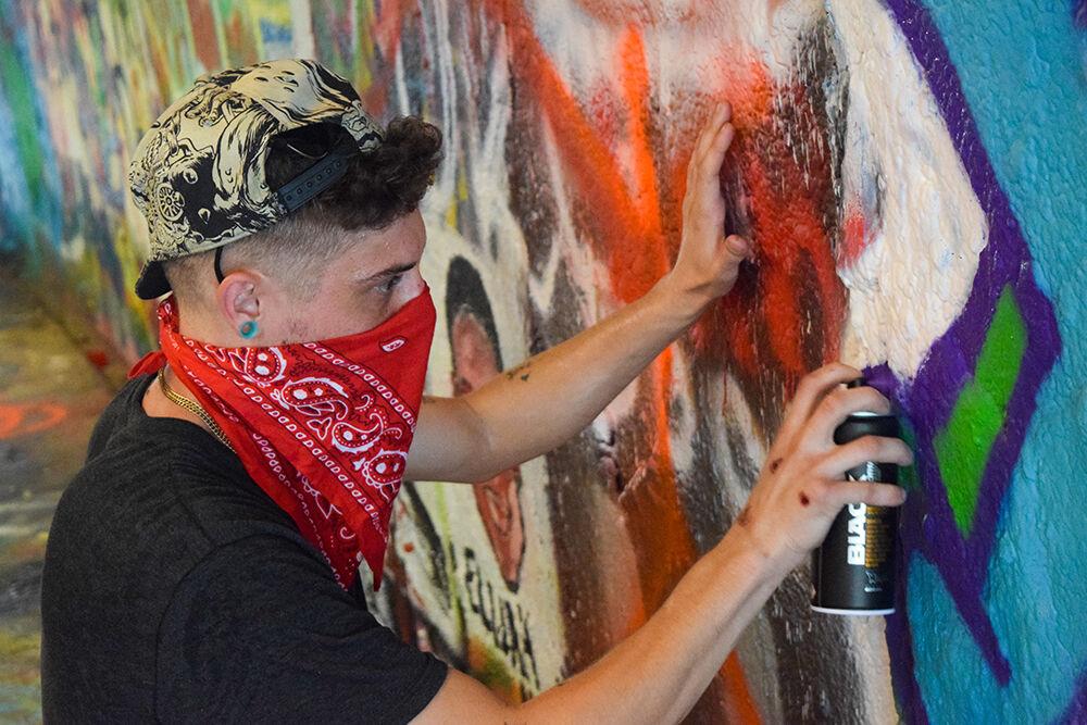 Mark Ross, a third-year studying mathematics, spray paints "Yolo" in the Free Expression Tunnel on Saturday, Aug 8, 2020. He goes by Lydic, and this was his first time spray painting.&#160;