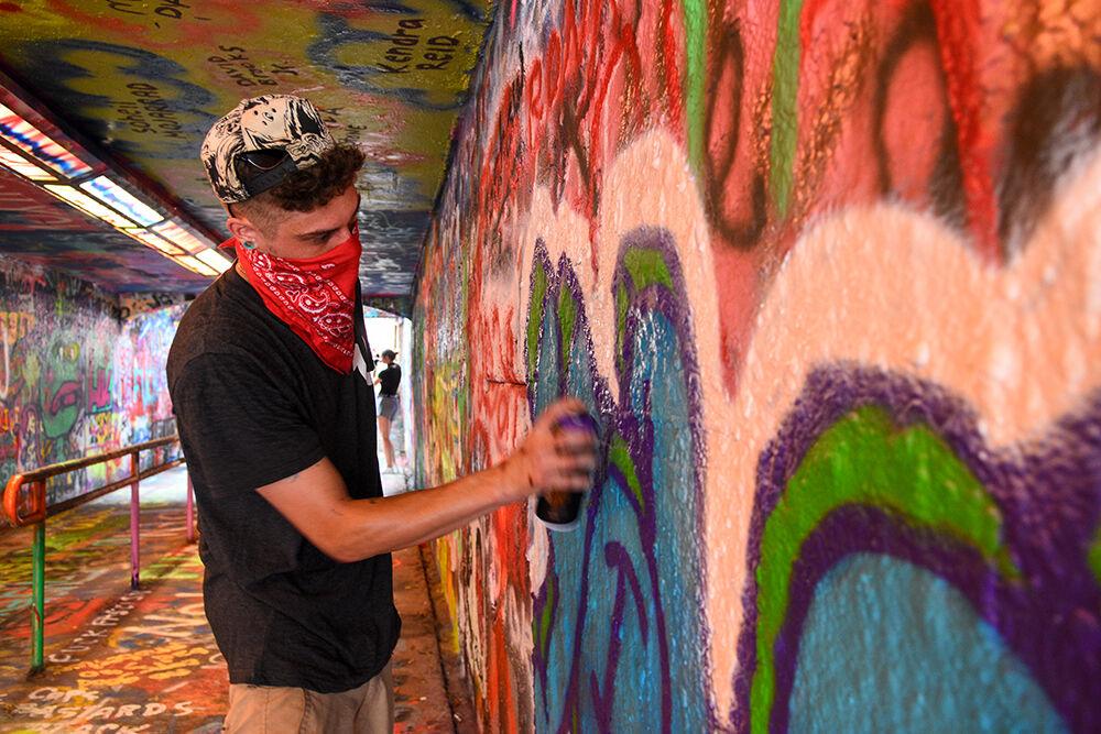 Mark Ross, a third-year studying mathematics, spray paints the word "YOLO" in the Free Expression Tunnel on Saturday, August 8, 2020.&#160;