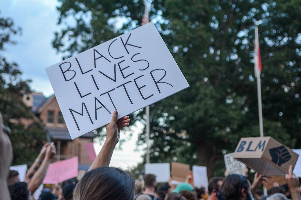Community members walk while holding signs at the Black Lives Matter Community March in downtown Raleigh on Friday, Aug. 28, 2020. The march included chants and speeches from marchers about racial issues.