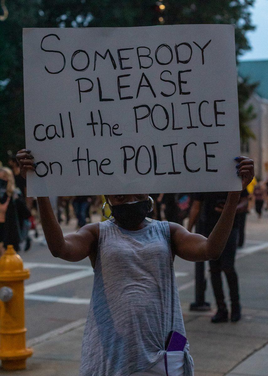 A protester holds a sign that reads "Somebody please call the police on the the police" during the Black Lives Matter protest on Friday, Aug. 28, 2020. On the matter of the protest, while she mentions that it was her first time coming out to one, she said that she "just had to come out in support."