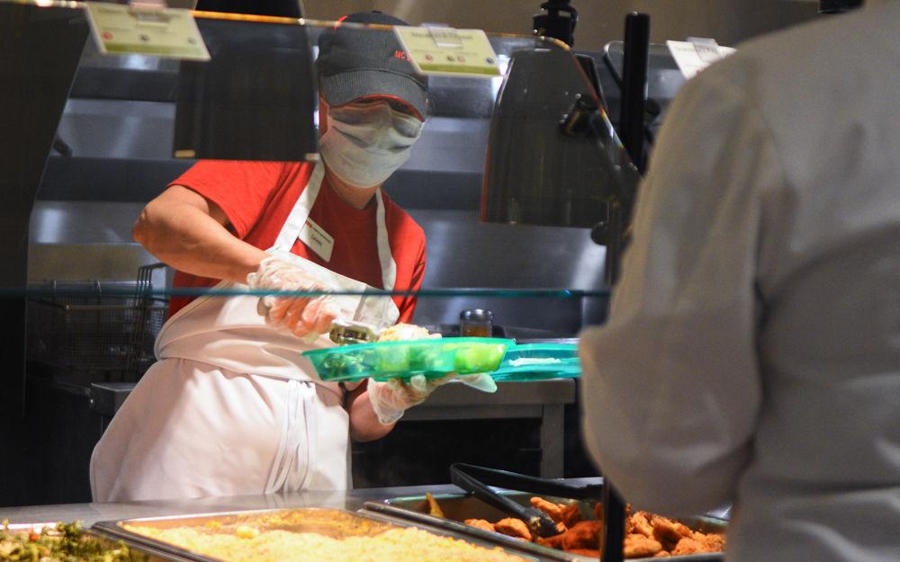 A food worker fills a guest's plate with food in Fountain Dining Hall during a run-through on July 13, 2020. Food workers in dining halls will hand plates off to each other before giving the final product to students.