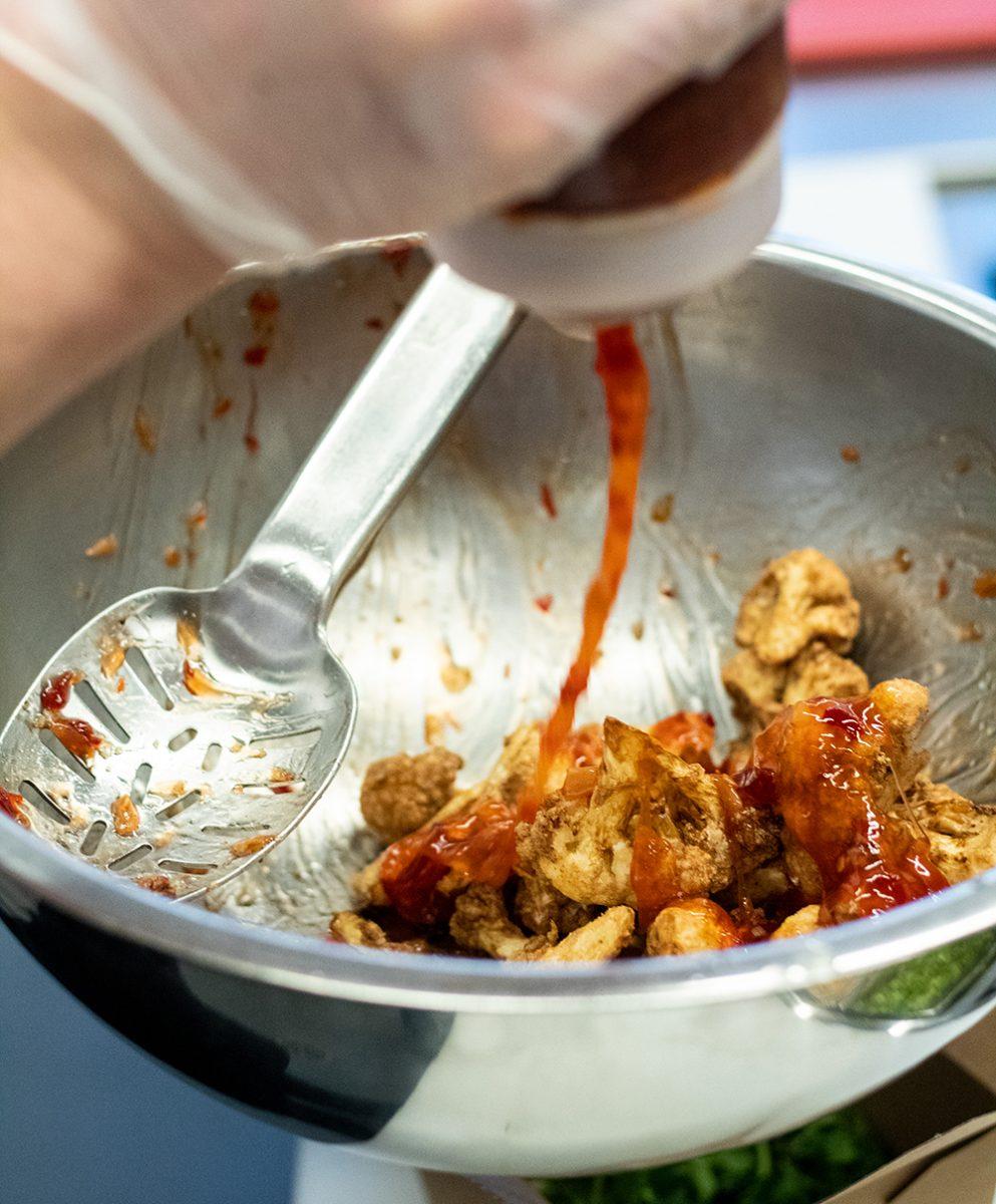 Cauliflower gets covered in sweet Thai Chili sauce in a mixing bowl in the kitchen of 1887 Bistro on Wednesday, Sept. 23, 2020.