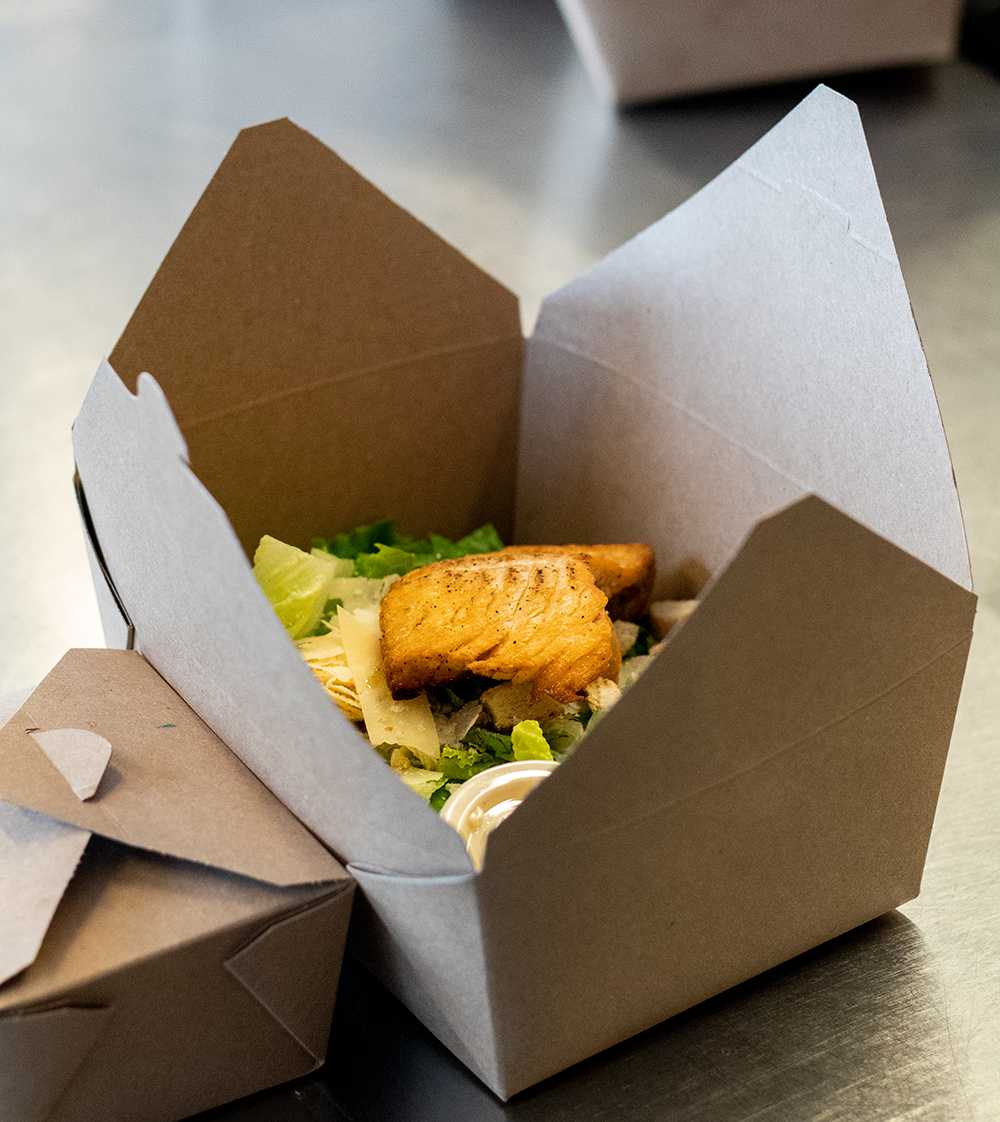 A Salmon Caesar Salad sits in a to-go box in the kitchen of 1887 Bistro on Wednesday, Sept. 23, 2020. Other salads 1887 Bistro provides include the Fruit and Nut Salad and the Asian Chopped Salad.