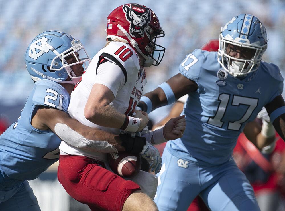 North Carolina's Chazz Surratt (21) sacks N.C. State quarterback Ben Finley (10) for a loss of 14 yards and forces a fumble in the third quarter at Kenan Stadium on Saturday, October 24, 2020 in Chapel Hill, N.C.