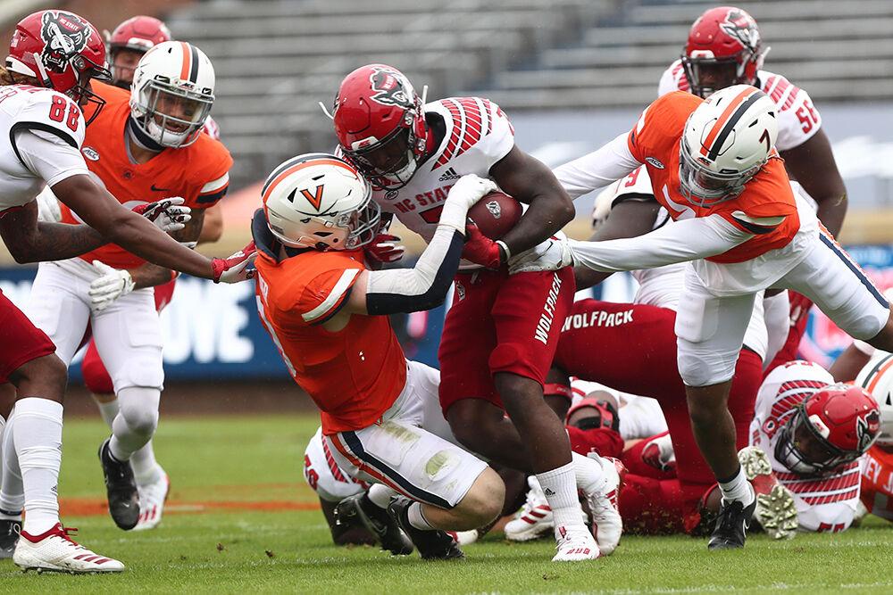 ERIN EDGERTON/THE DAILY PROGRESS A North Carolina State Wolfpack player is tackled by Virginia Cavaliers during a game against North Carolina State Wolfpack on Saturday at Scott Stadium in Charlottesville.