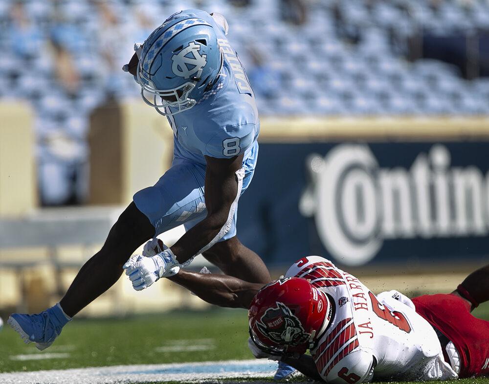 North Carolina's Michael Carter (8) scores on a 16 yard rush in the first quarter ahead of N.C. State's Jakeen Harris (6) to give the Tar Heels' a 7-0 lead at Kenan Stadium on Saturday, October 24, 2020 in Chapel Hill, N.C.