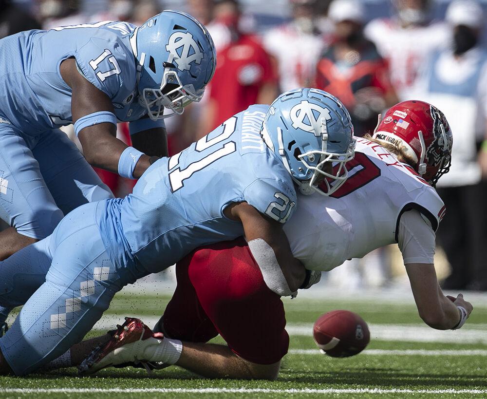 North Carolina's Chazz Surratt (21) sacks N.C. State quarterback Ben Finley (10) for a loss of 14 yards and forces a fumble in the third quarter at Kenan Stadium on Saturday, October 24, 2020 in Chapel Hill, N.C.
