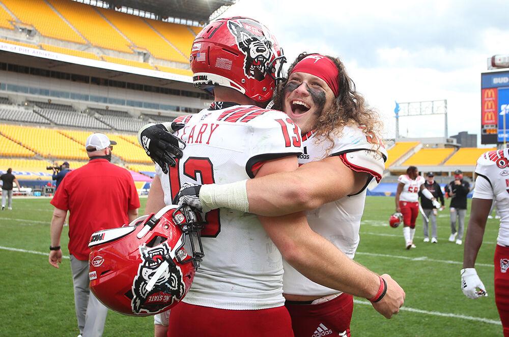 Oct 3, 2020; Pittsburgh, Pennsylvania, USA; North Carolina State Wolfpack quarterback Devin Leary (13) and linebacker Drake Thomas (32) celebrate after defeating the Pittsburgh Panthers at Heinz Field. The Wolfpack won 30-29. Mandatory Credit: Charles LeClaire-USA TODAY Sports