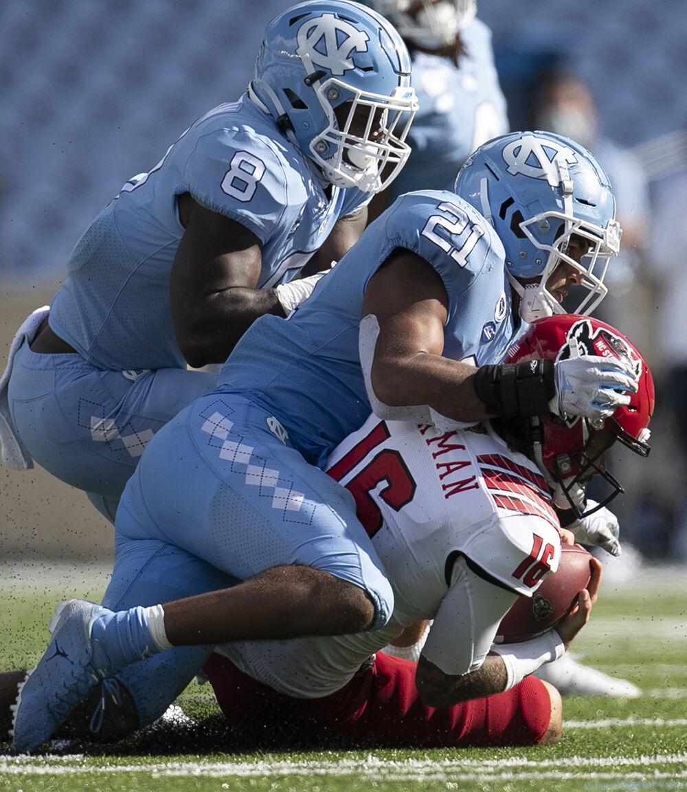 N.C. State quarterback Bailey Hockman (16) is sacked by North Carolina's Chazz Surratt (21) and Khadry Jackson (8) in the fourth quarter at Kenan Stadium on Saturday, October 24, 2020 in Chapel Hill, N.C.