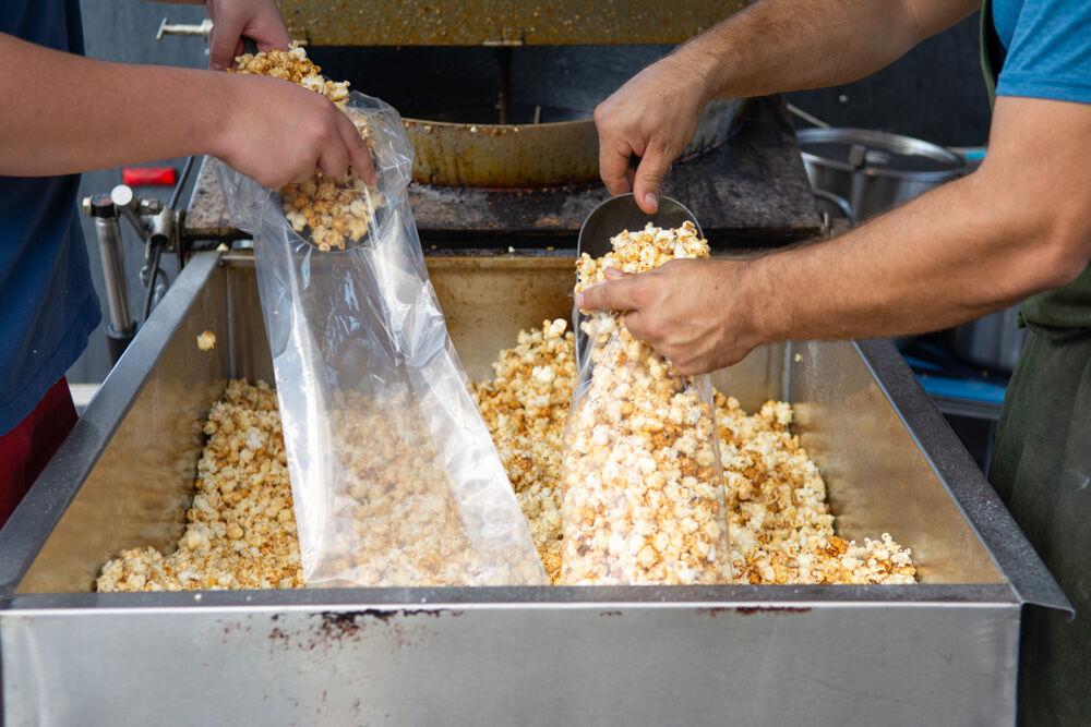 Workers at the Carolina Kettle Corn Lions Club booth bag fresh popcorn at the NC State Fair Food days event on Wednesday, Oct. 21. 2020. The event was hosted from Oct. 15-25 in wake of the 2020 state fair being cancelled.
