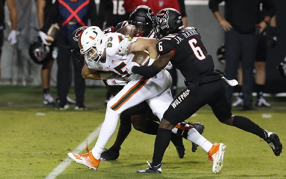 Miami tight end Will Mallory (85) is tackled by N.C. State safety Jakeen Harris (6), Tyler Baker-Williams (13) and Cecil Powell (4) during the first half of N.C. State&#8217;s game against Miami at Carter-Finley Stadium in Raleigh, N.C., Friday, Nov. 6, 2020.