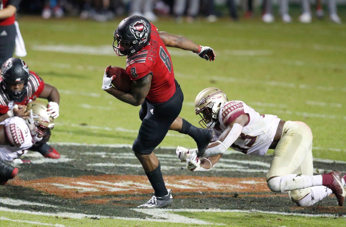 N.C. State running back Ricky Person Jr. (8) tries to escape from Florida State linebacker Amari Gainer (33) during the first half of N.C. State&#8217;s game against Florida State at Carter-Finley Stadium in Raleigh, N.C., Saturday, Nov. 14, 2020.