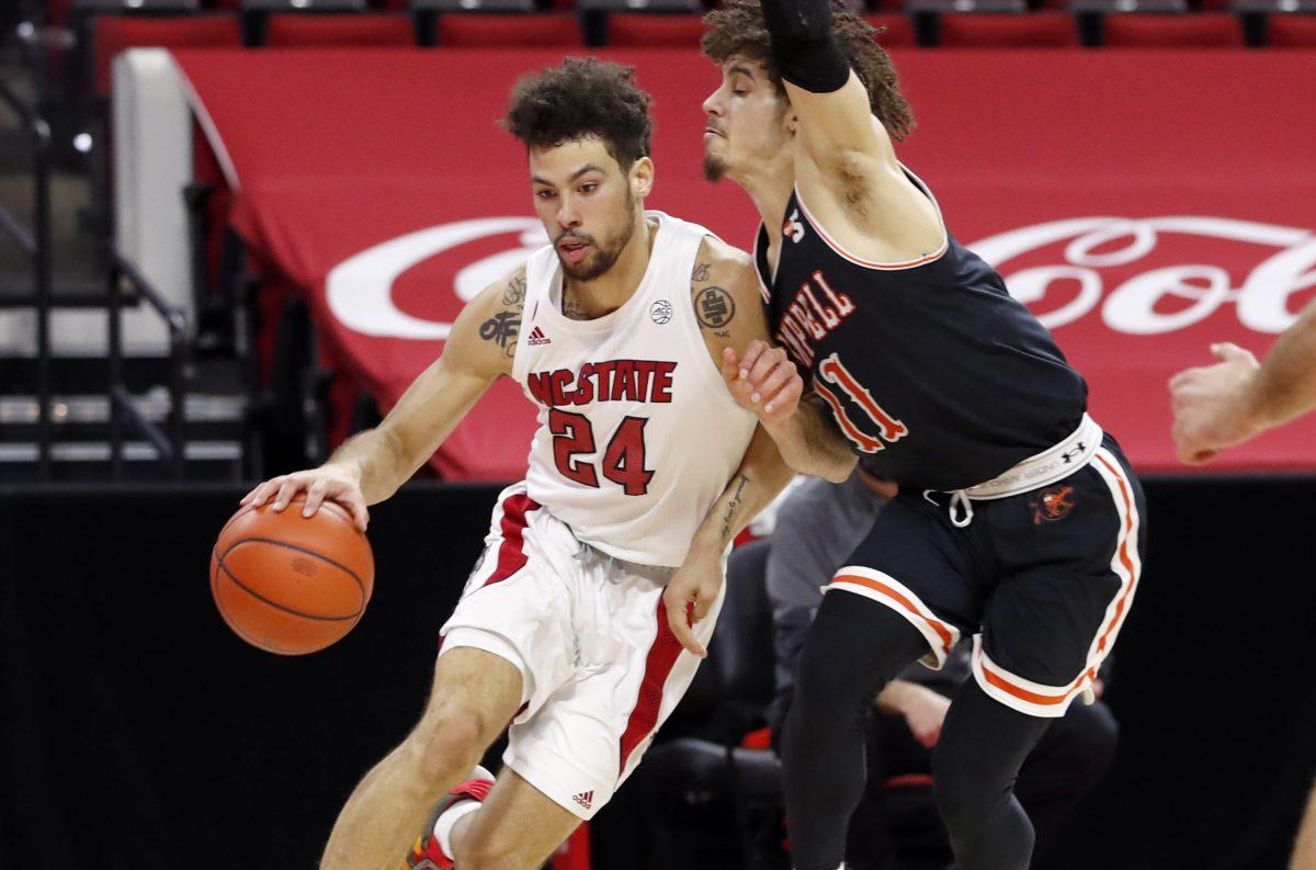 N.C. State's Devon Daniels (24) drives around Campbell's Jordan Whitfield (11) during the first half of N.C. State&#8217;s game against Campbell at PNC Arena in Raleigh, N.C., Saturday, Dec. 19, 2020.