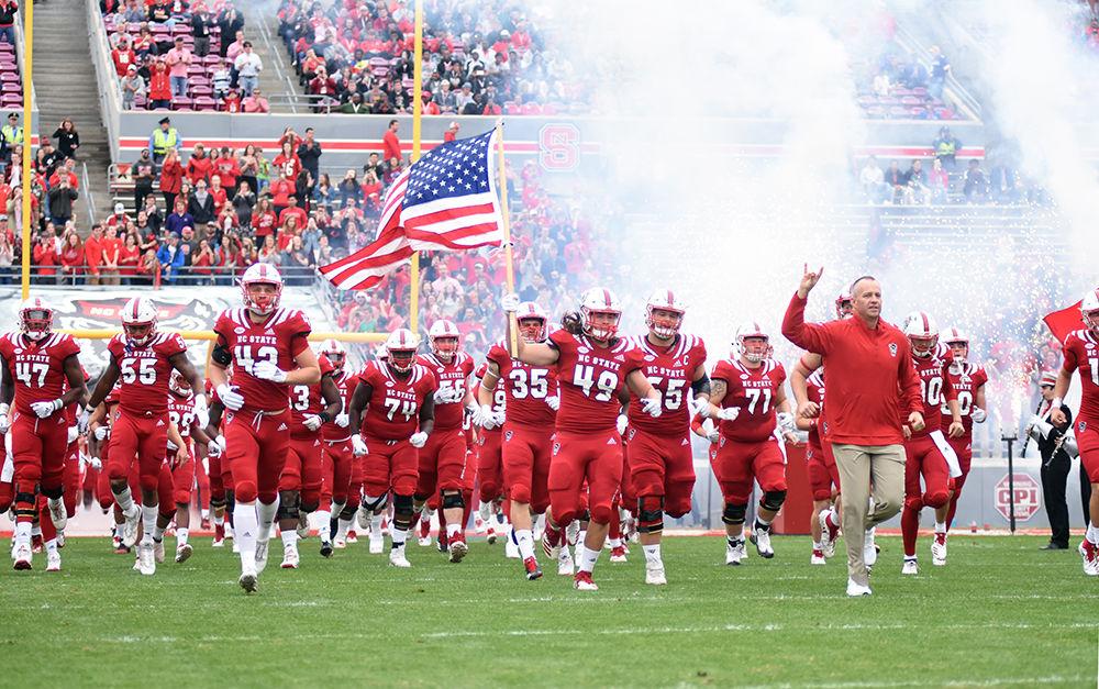 Freshman linebacker Seth Williams holds up the American flag as the team ruses the field during the game against ECU on Saturday, Dec. 1, 2018 in Carter-Finley Stadium. The Wolfpack beat the Pirates 58-3, for a 9-3 season.