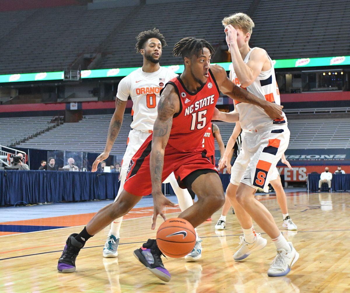 Jan 31, 2021; Syracuse, New York, USA; North Carolina State Wolfpack forward Manny Bates (15) drives the ball along the baseline past Syracuse Orange forward Alan Griffin (0) ans forward Marek Dolezaj (21) in the second half at the Carrier Dome. Mandatory Credit: Mark Konezny-USA TODAY Sports