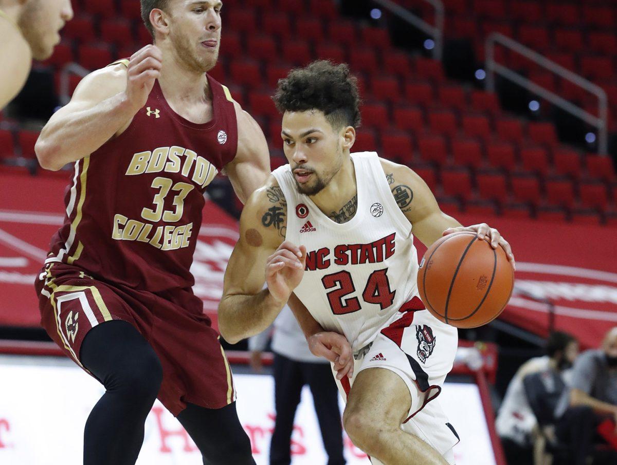 N.C. State's Devon Daniels (24) drives by Boston College's James Karnik (33) during the first half of N.C. State&#8217;s game against Boston College at PNC Arena in Raleigh, N.C., Wednesday, December 30, 2020.