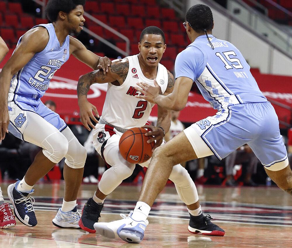 N.C. State's Shakeel Moore (2) drives between North Carolina's Kerwin Walton (24), left and Garrison Brooks (15) during the first half of N.C. State&#8217;s game against UNC at PNC Arena in Raleigh, N.C., Tuesday, December 22, 2020.