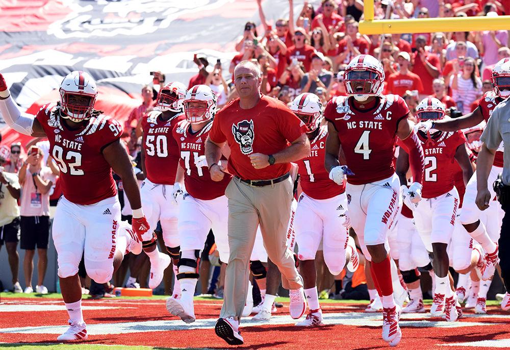 Head coach Dave Doeren runs out of the tunnel with the team behind him before their game against ECU on Saturday, August 31, 2019 in Carter-Finley Stadium. The Pack had a 34-6 win over the Pirates.